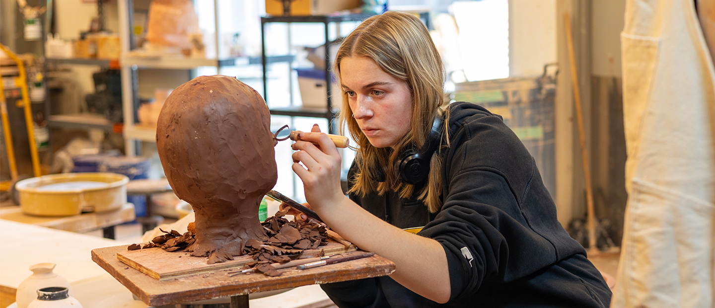 Seton Hill Student working on a clay sculpture.