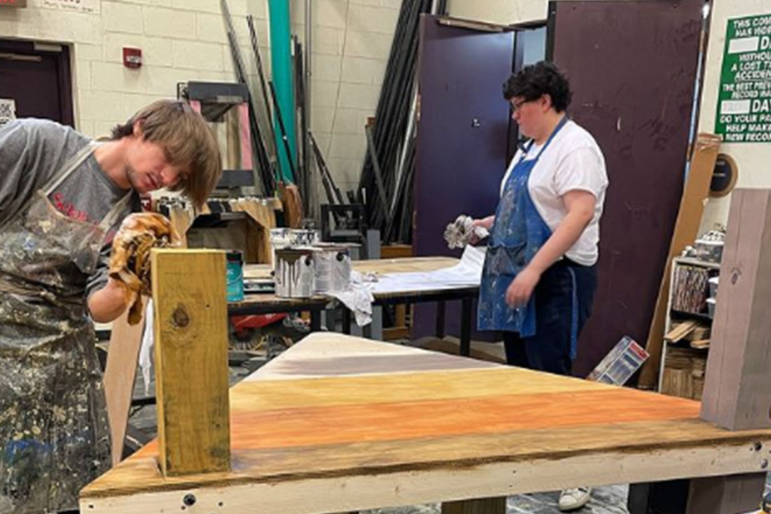 Photo of Students Painting Wood Graining on a set piece for Peter and the Starcatcher