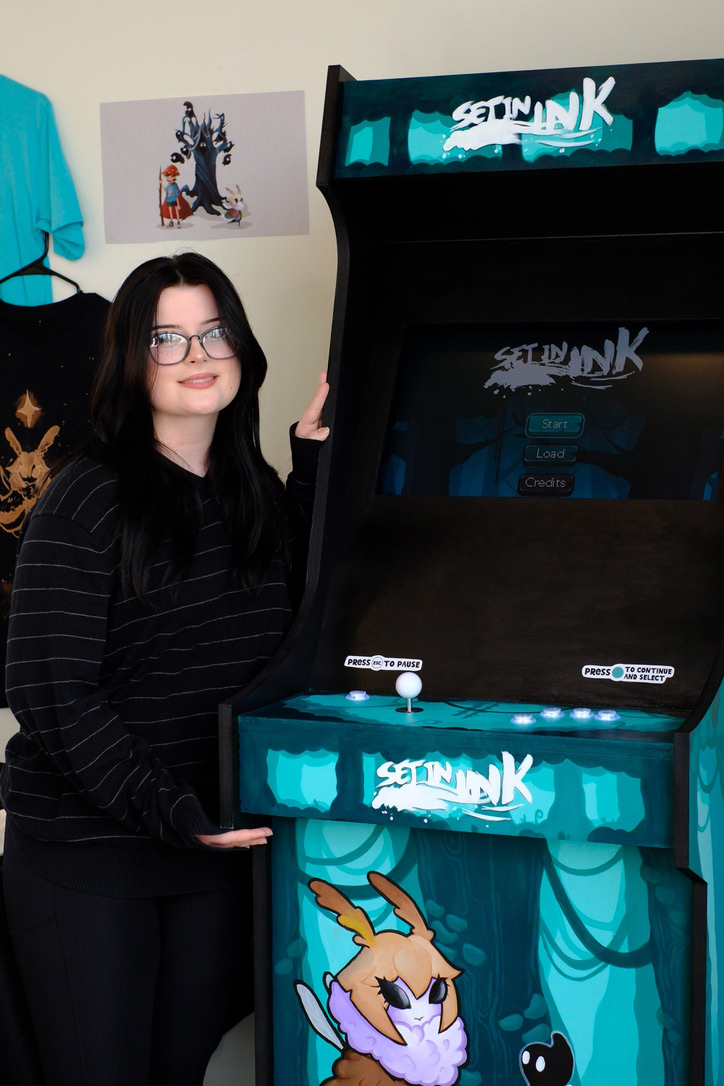 Female student standing next to arcade game cabinet