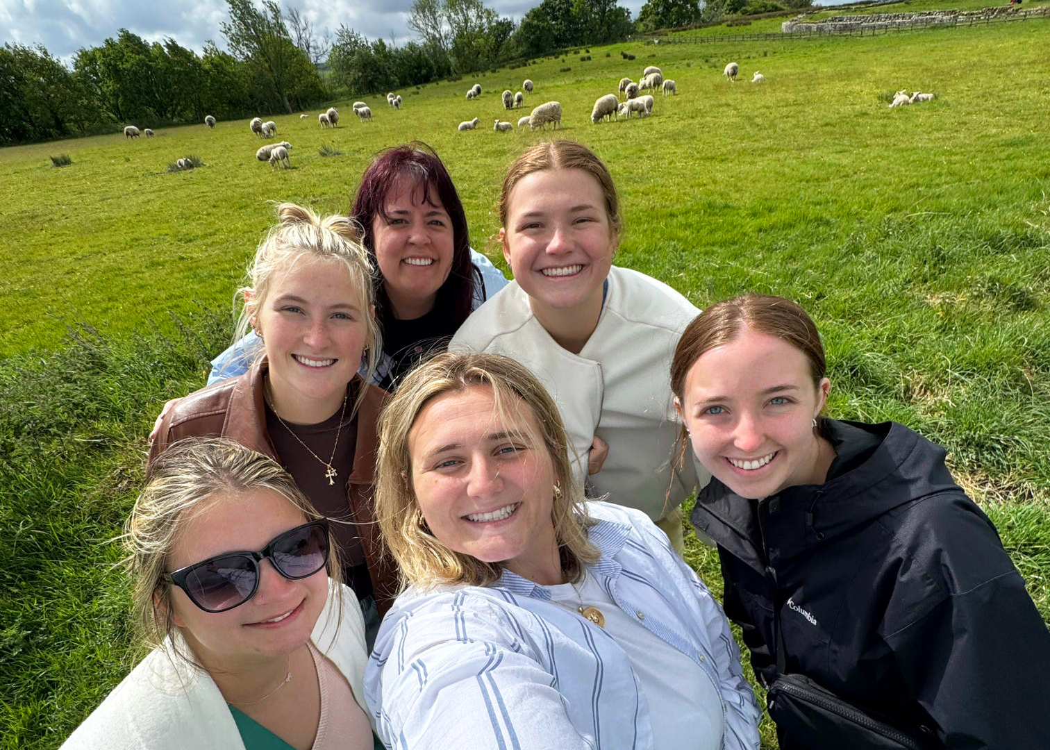 Group of girls standing with sheep.